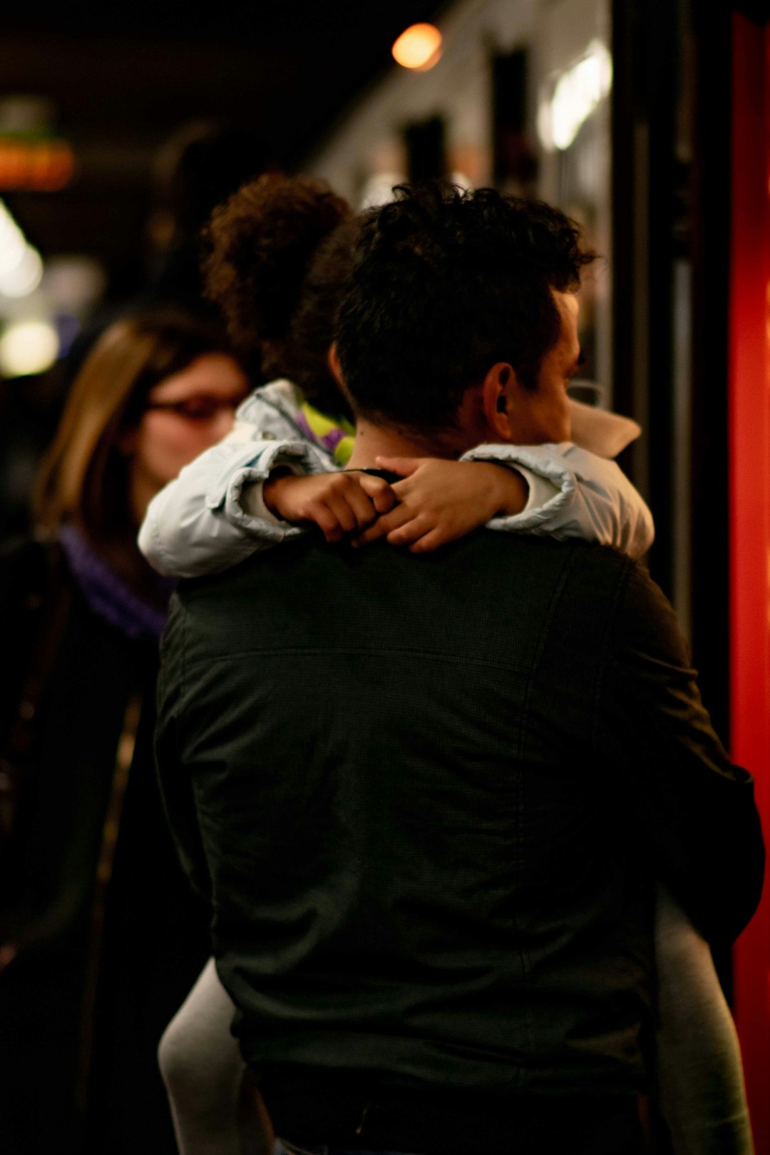 man in black suit jacket hugging woman in blue long sleeve shirt