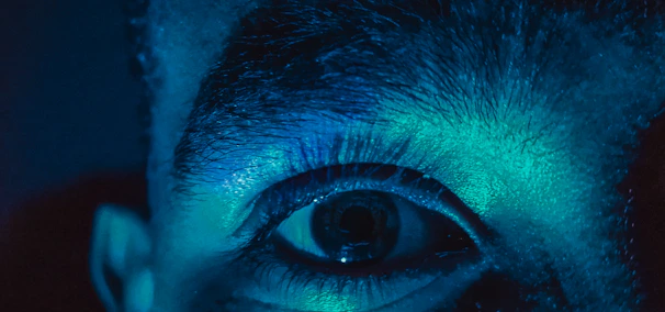 Close-up of a researcher examining eye scans under blue light in a clinical lab.