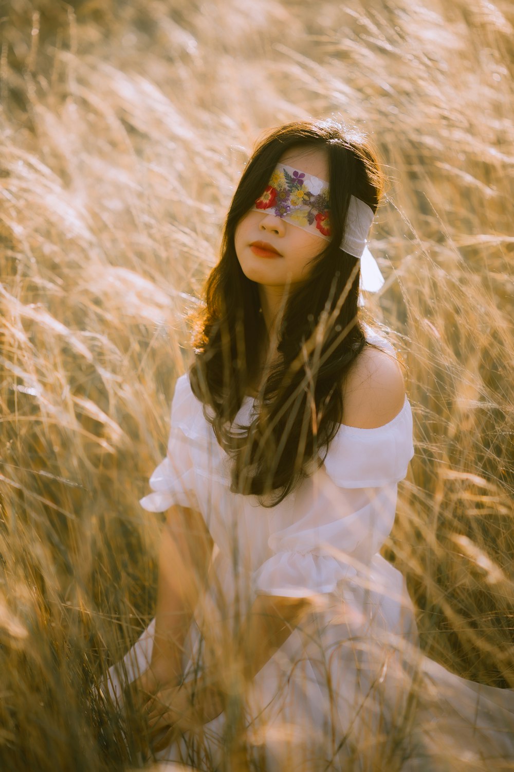 woman in white dress wearing black sunglasses standing on brown grass field during daytime