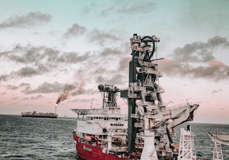 red and white ship on sea under cloudy sky during daytime