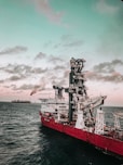 red and white ship on sea under cloudy sky during daytime