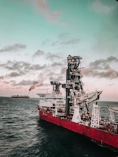 red and white ship on sea under cloudy sky during daytime