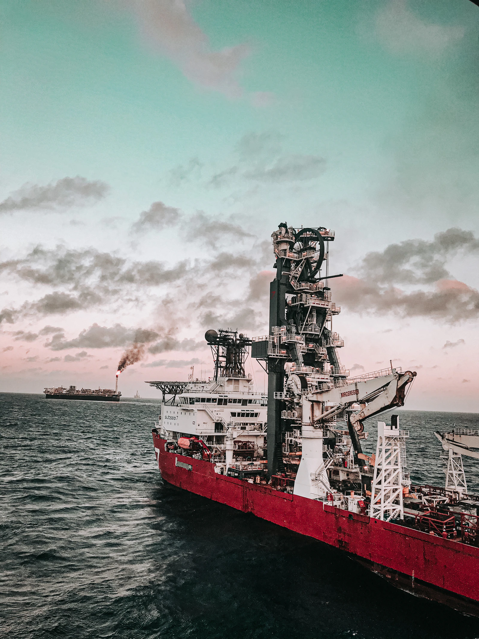 A red and white ship at sea under a cloudy sky