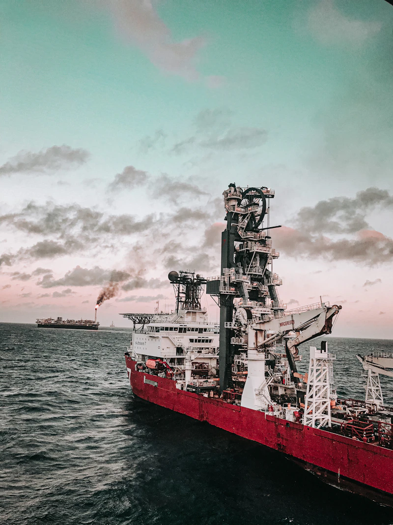 Red and white support vessel beside an offshore structure