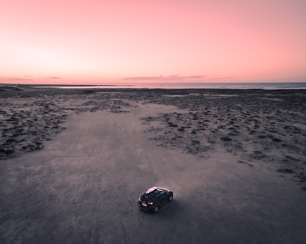 voiture noire sur le sable gris au coucher du soleil