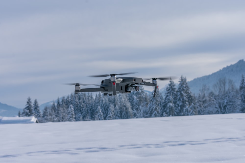 black helicopter flying over snow covered ground during daytime