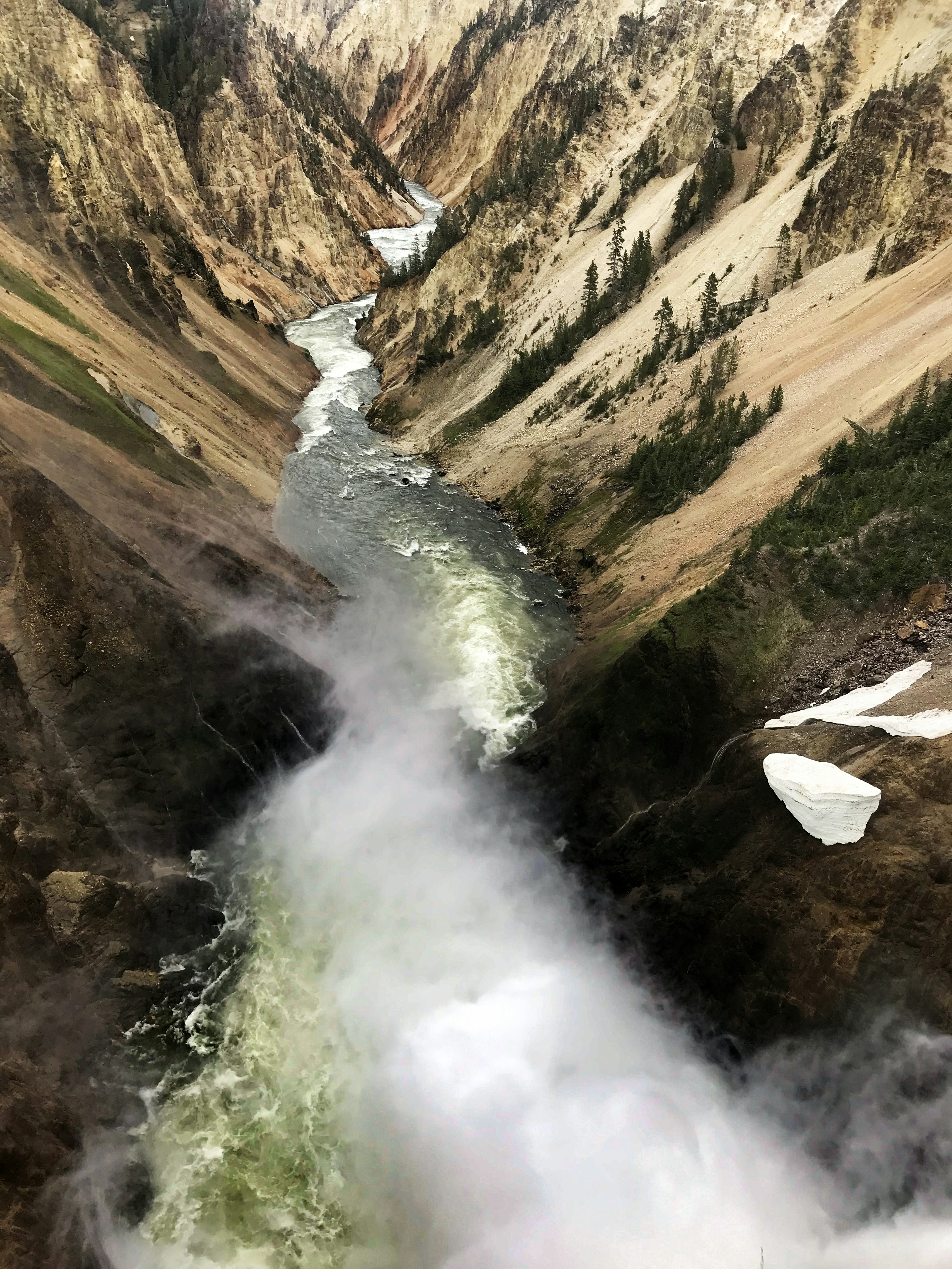 water falls on brown rocky mountain during daytime