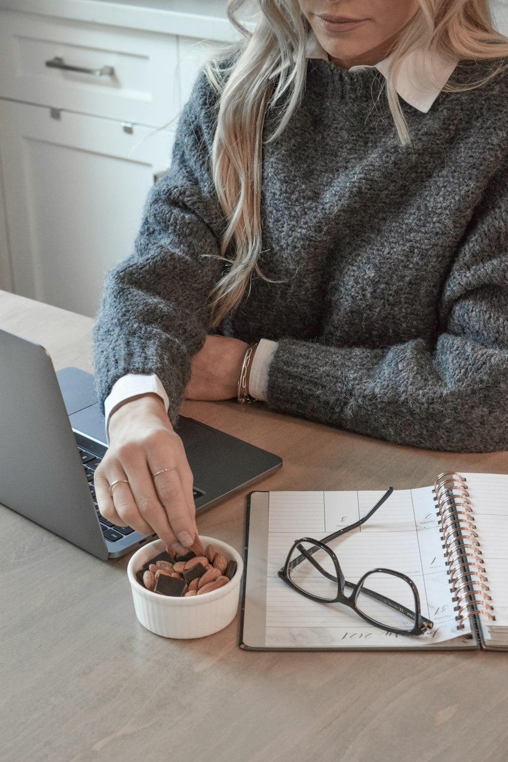 woman in gray sweater holding white ceramic mug