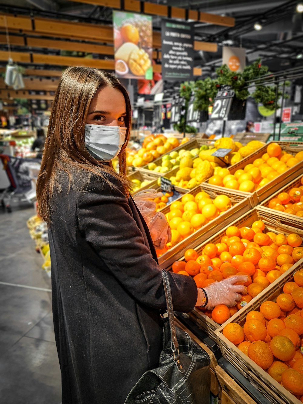 woman in black leather jacket standing in front of orange fruits