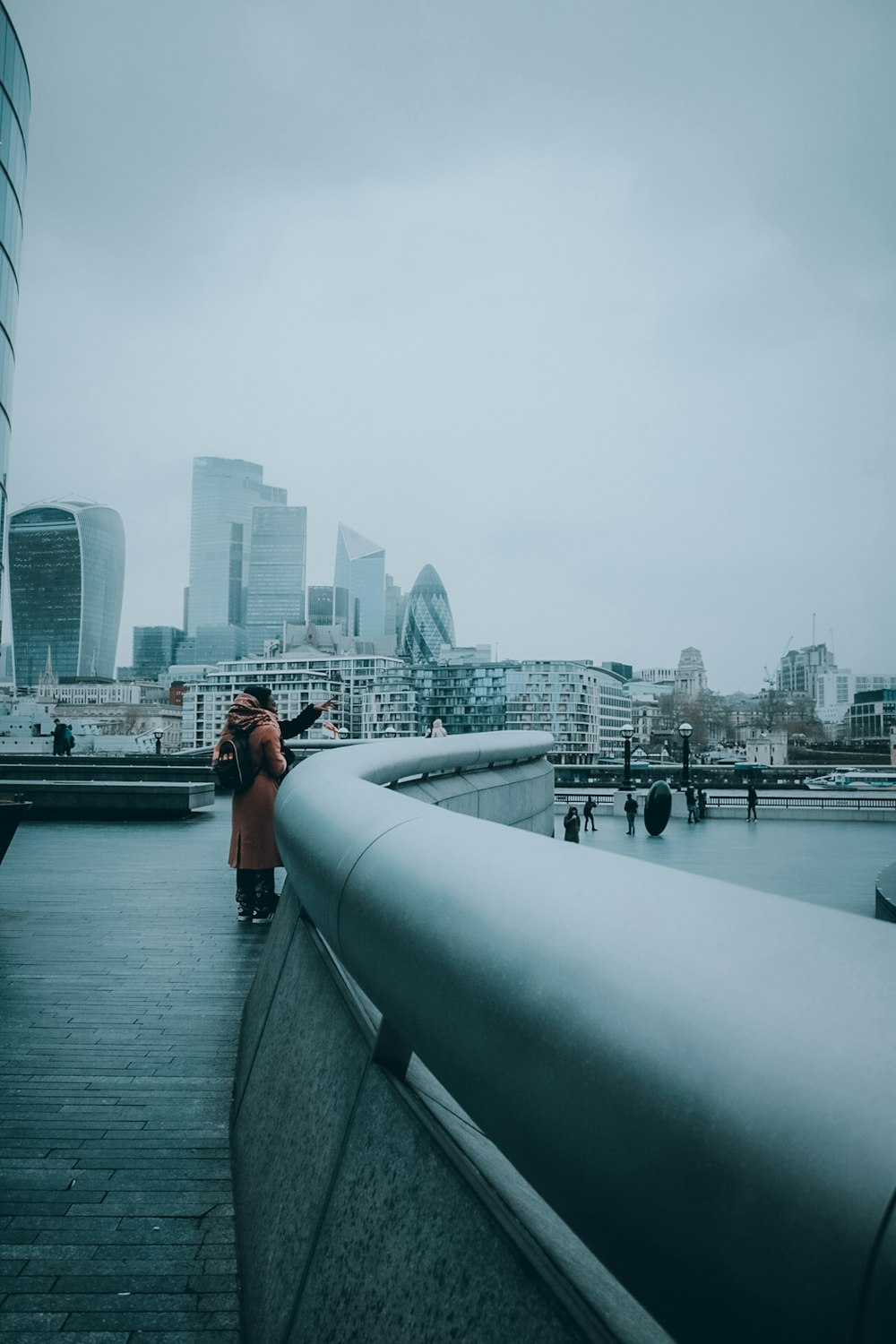 woman in red shirt sitting on gray concrete bridge during daytime