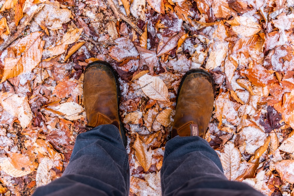 person wearing blue denim jeans and brown leather boots