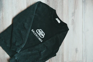 Close-up of a black and yellow DSD1 Records hoodie laid out on a dark wooden surface.