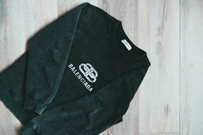 Close-up of a black and yellow DSD1 Records hoodie laid out on a dark wooden surface.