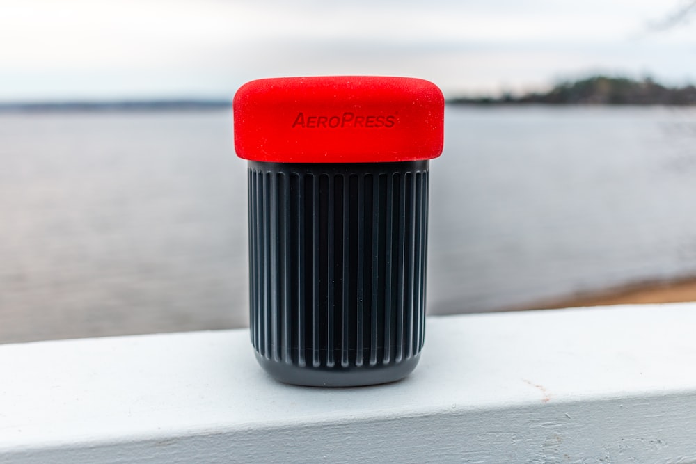 Recipiente de plástico rojo y negro sobre mesa blanca