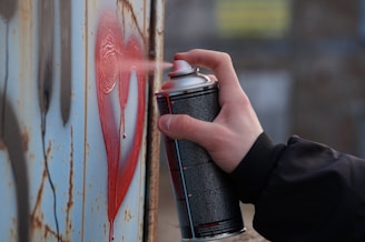 person holding black and red spray can