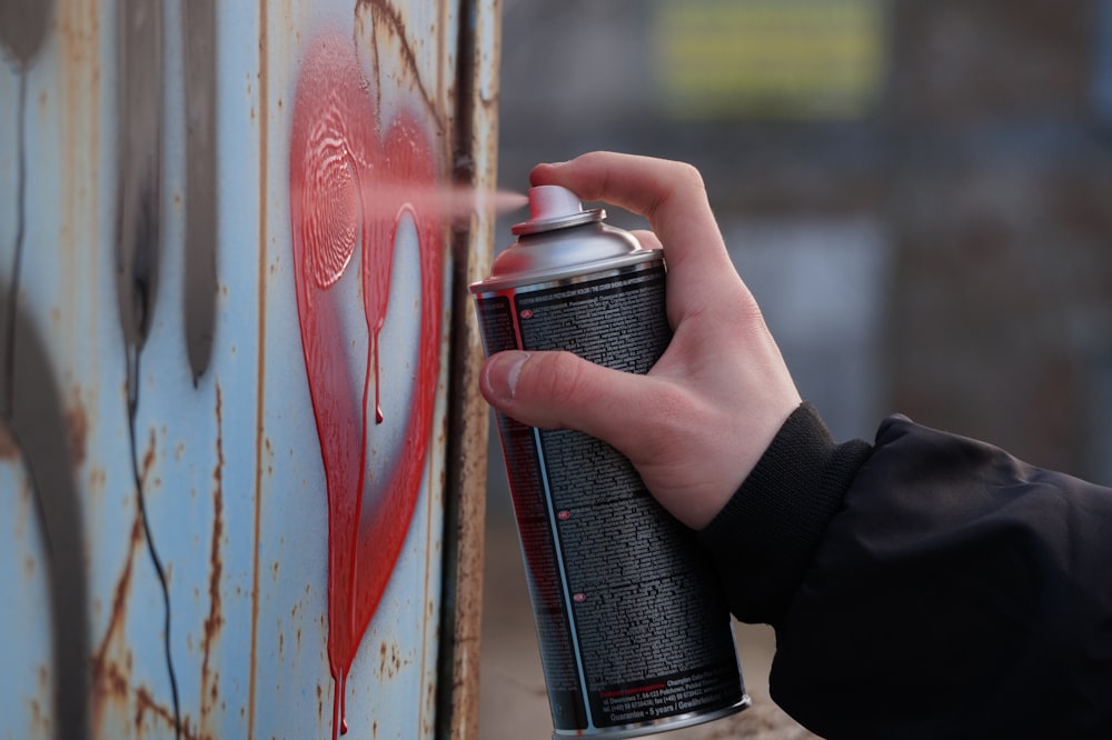 person holding black and red spray can