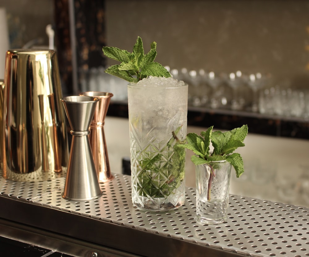 verre à boire transparent avec des feuilles vertes sur la table