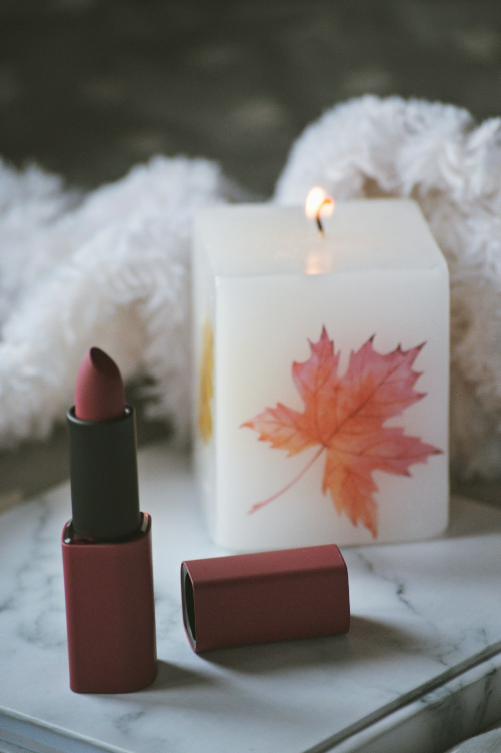 red lipstick beside white candle