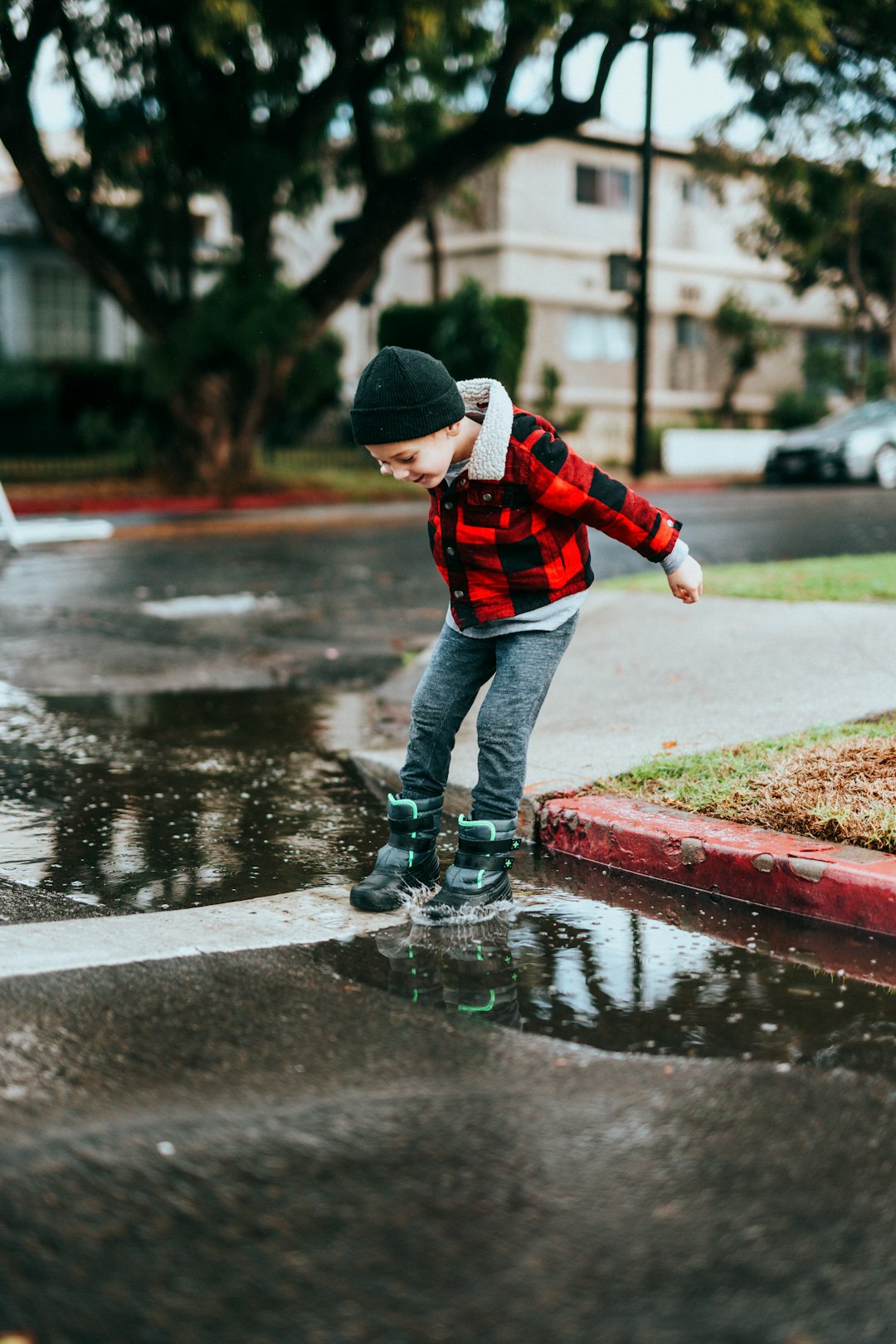 child in red jacket and blue denim jeans standing on concrete pathway during daytime