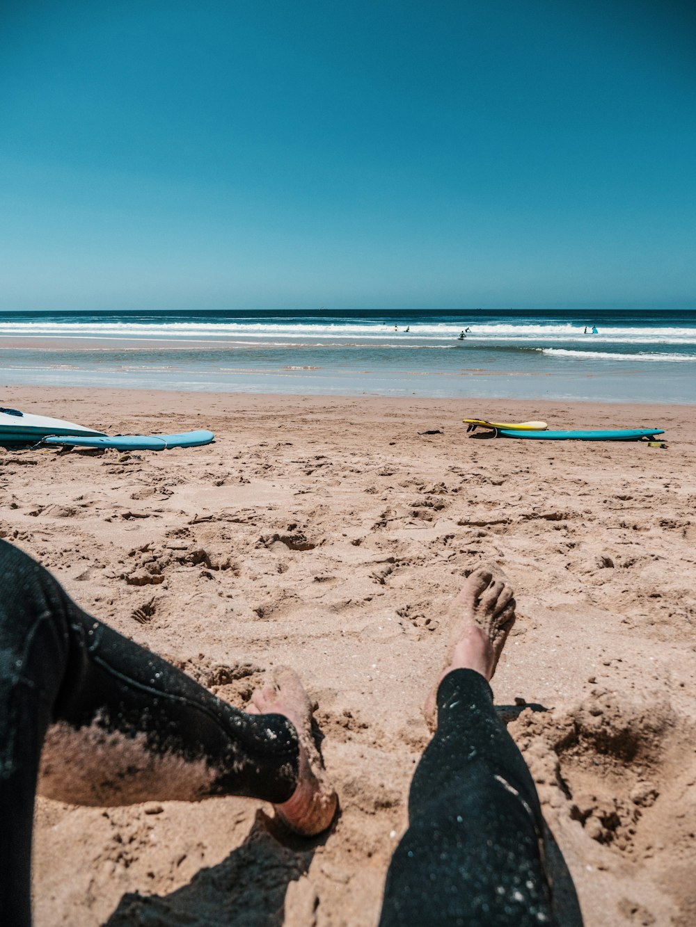 person in black pants sitting on beach