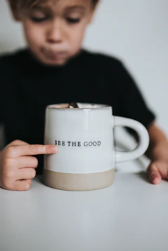 man in black long sleeve shirt holding white ceramic mug