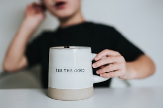 woman in black shirt holding white ceramic mug