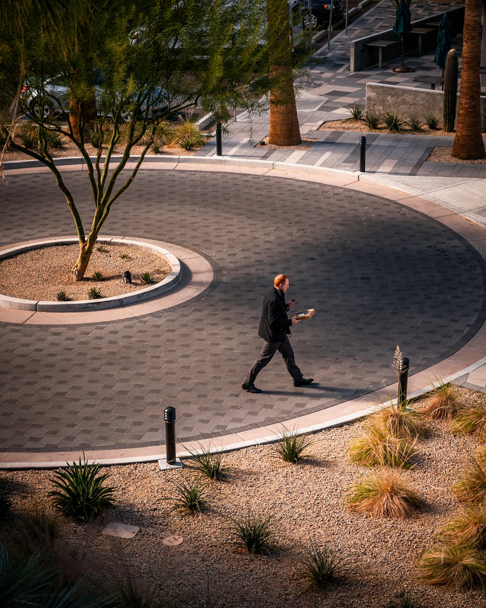 man in black jacket walking on gray concrete pathway during daytime