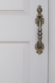 Elegant white door with decorative molding and vintage-style handle.