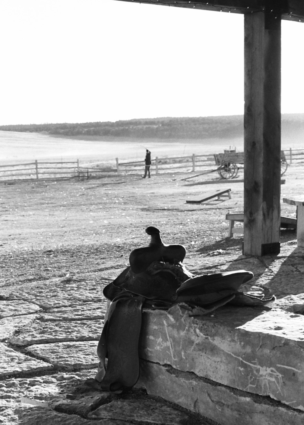 Foto en escala de grises de un hombre sentado en una silla cerca de la playa