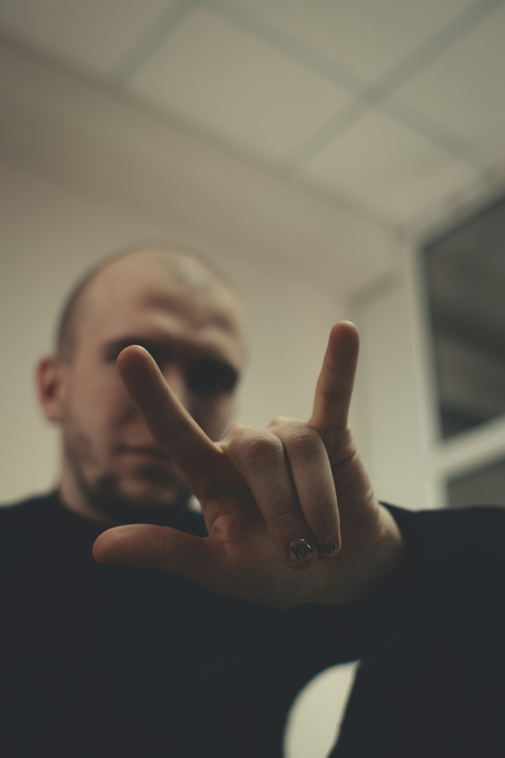 man in black crew neck shirt showing his middle finger
