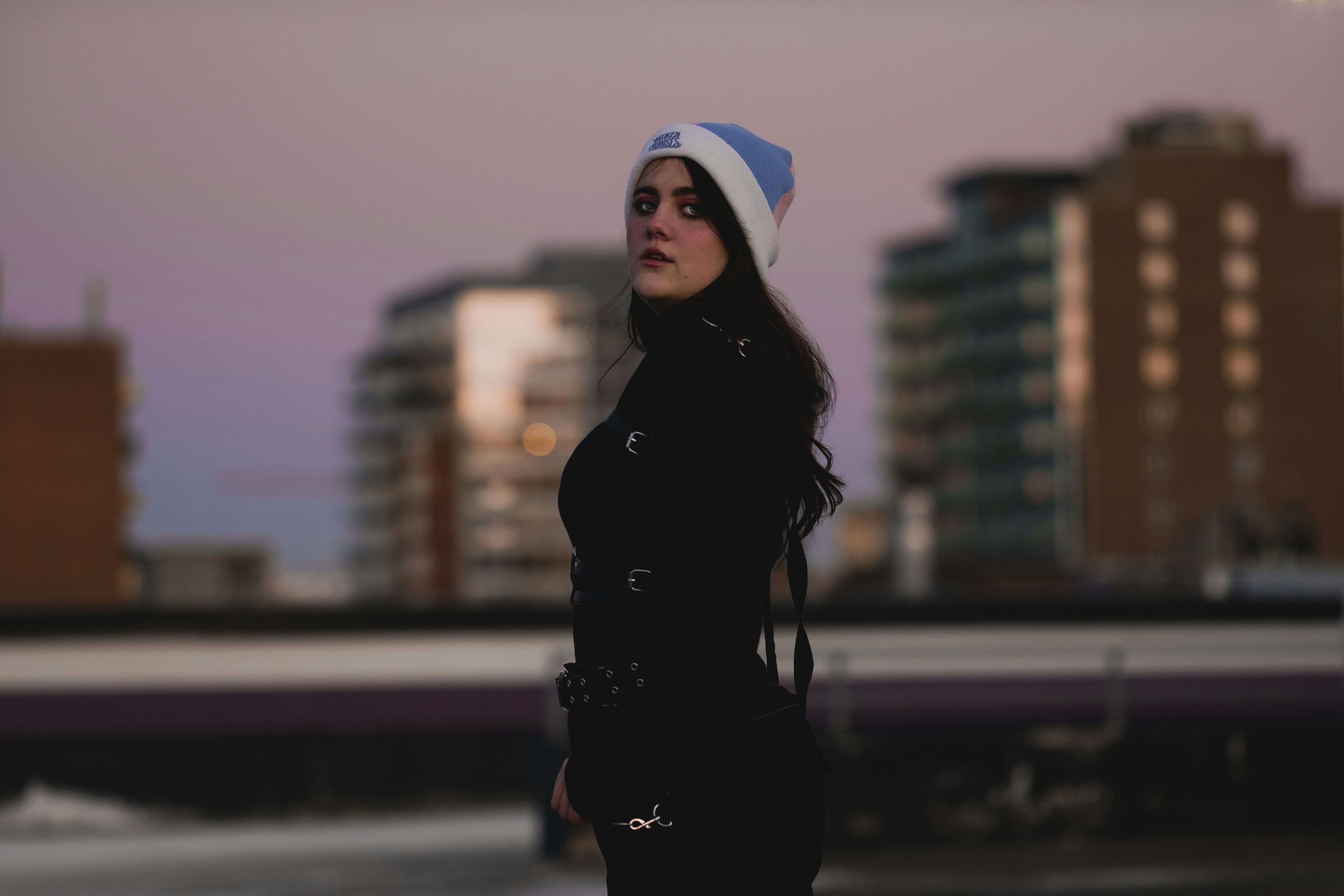 woman in black coat and blue knit cap standing on field during daytime