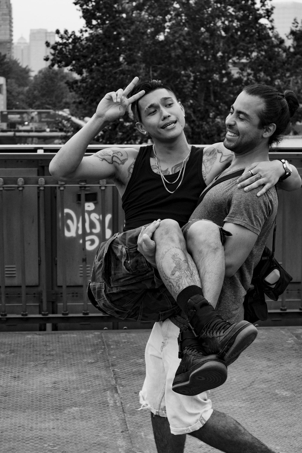 grayscale photo of 2 men sitting on concrete pavement