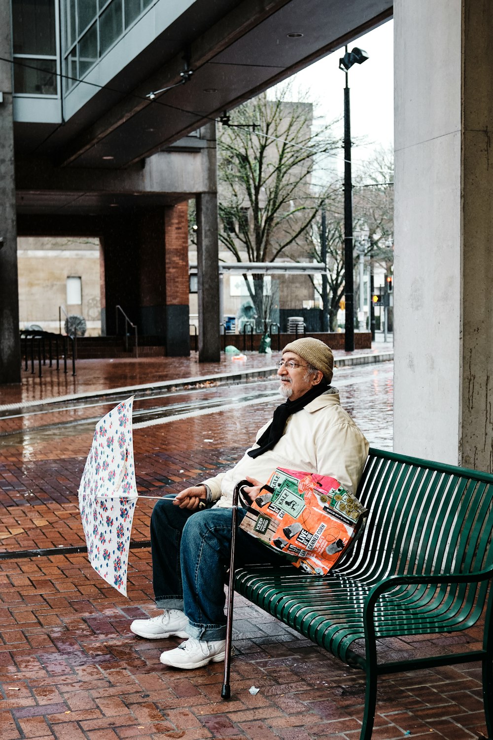woman in white jacket and blue denim jeans sitting on green bench