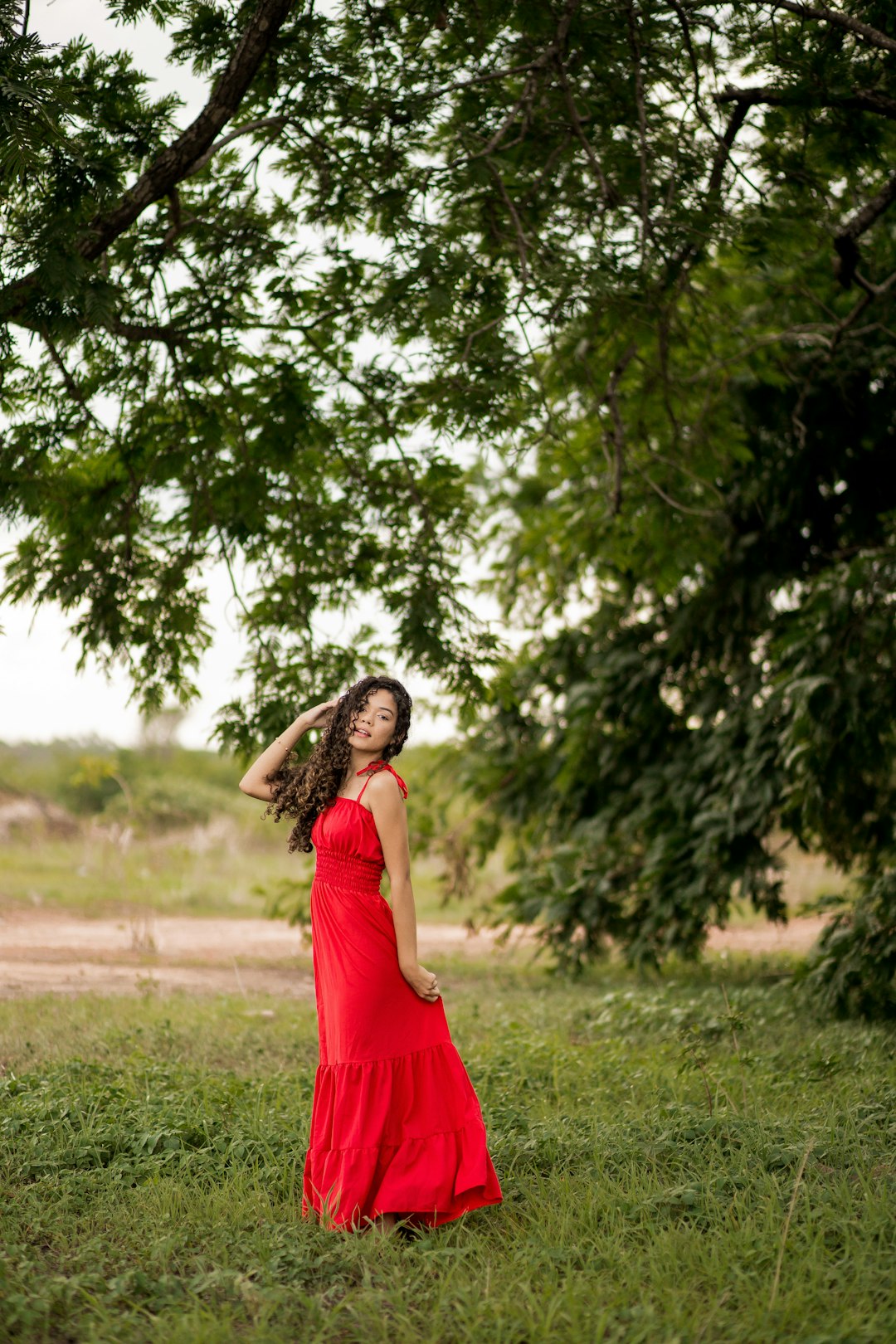 woman in red sleeveless dress standing on green grass field during daytime