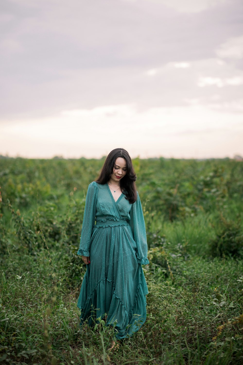 woman in green long sleeve dress standing on green grass field during daytime