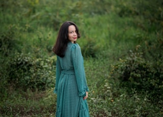 woman in green dress standing on green grass field during daytime