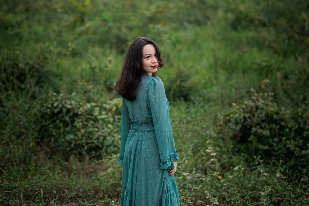 woman in green dress standing on green grass field during daytime