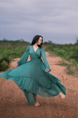 woman in green long sleeve dress standing on brown field during daytime