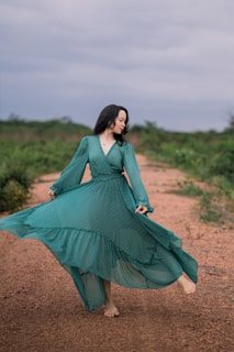 woman in green long sleeve dress standing on brown field during daytime