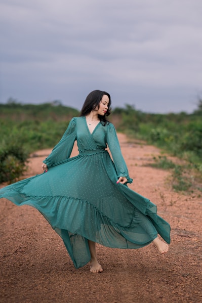 woman in green long sleeve dress standing on brown field during daytime