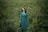 woman in blue long sleeve dress standing on green grass field during daytime