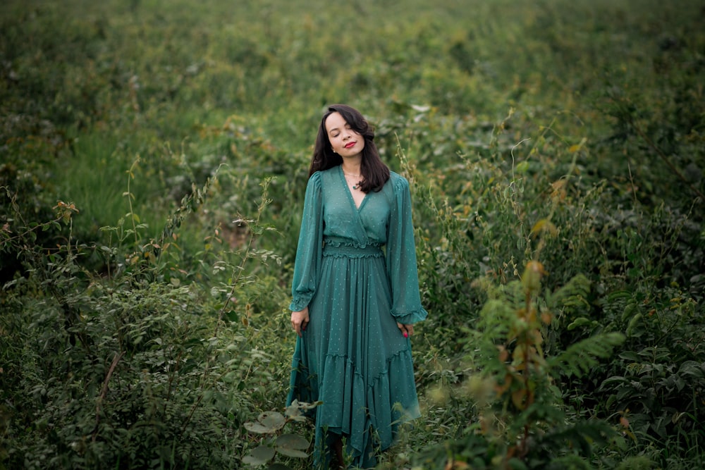 Frau im blauen langärmeligen Kleid tagsüber auf grünem Rasen stehend
