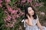 woman in white and black plaid dress shirt standing beside pink flowers
