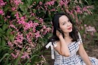 woman in white and black plaid dress shirt standing beside pink flowers