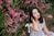 woman in white and black plaid dress shirt standing beside pink flowers