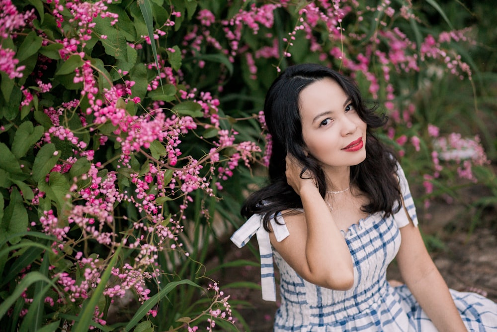 woman in white and black plaid dress shirt standing beside pink flowers