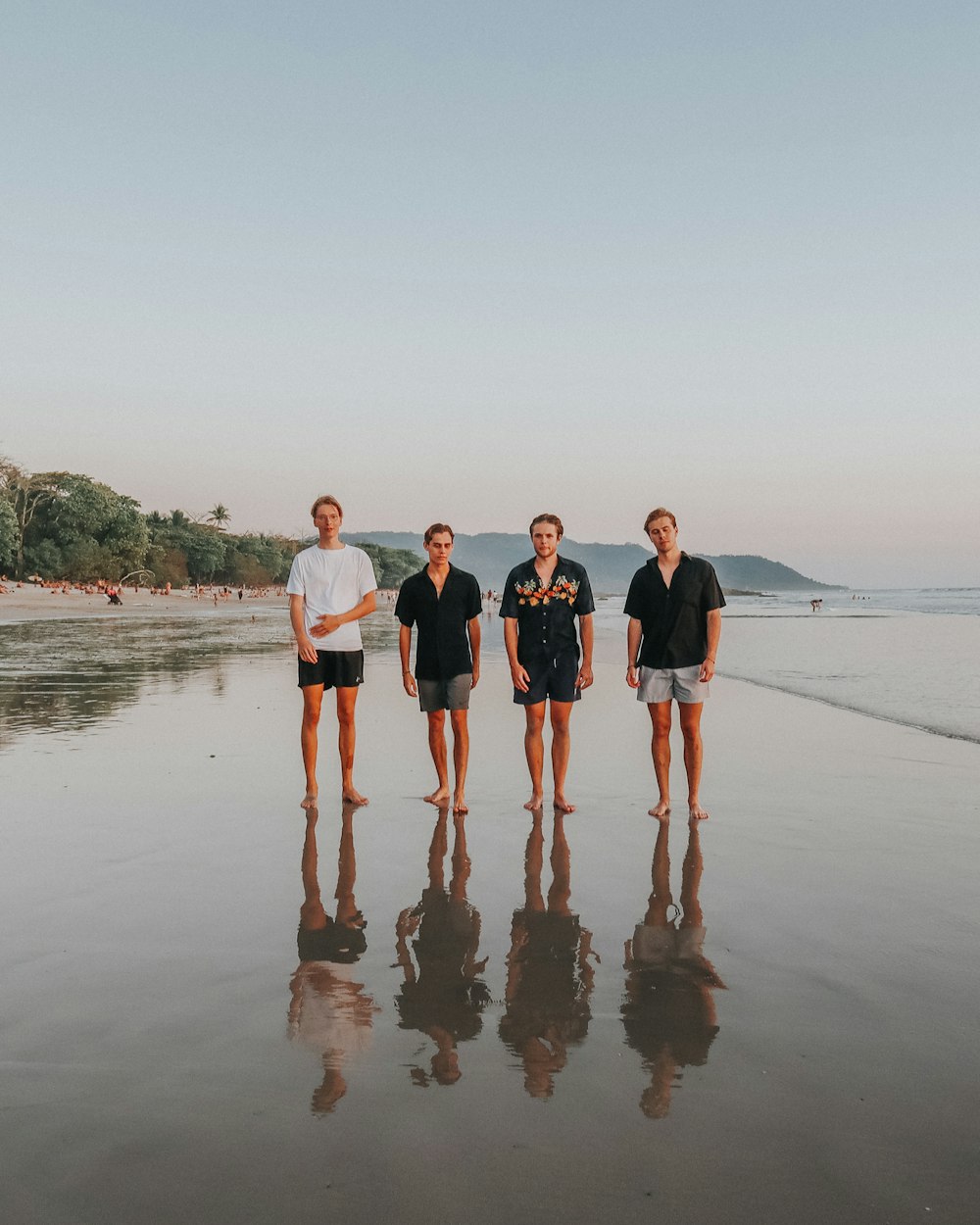 3 women and 2 men standing on beach during daytime