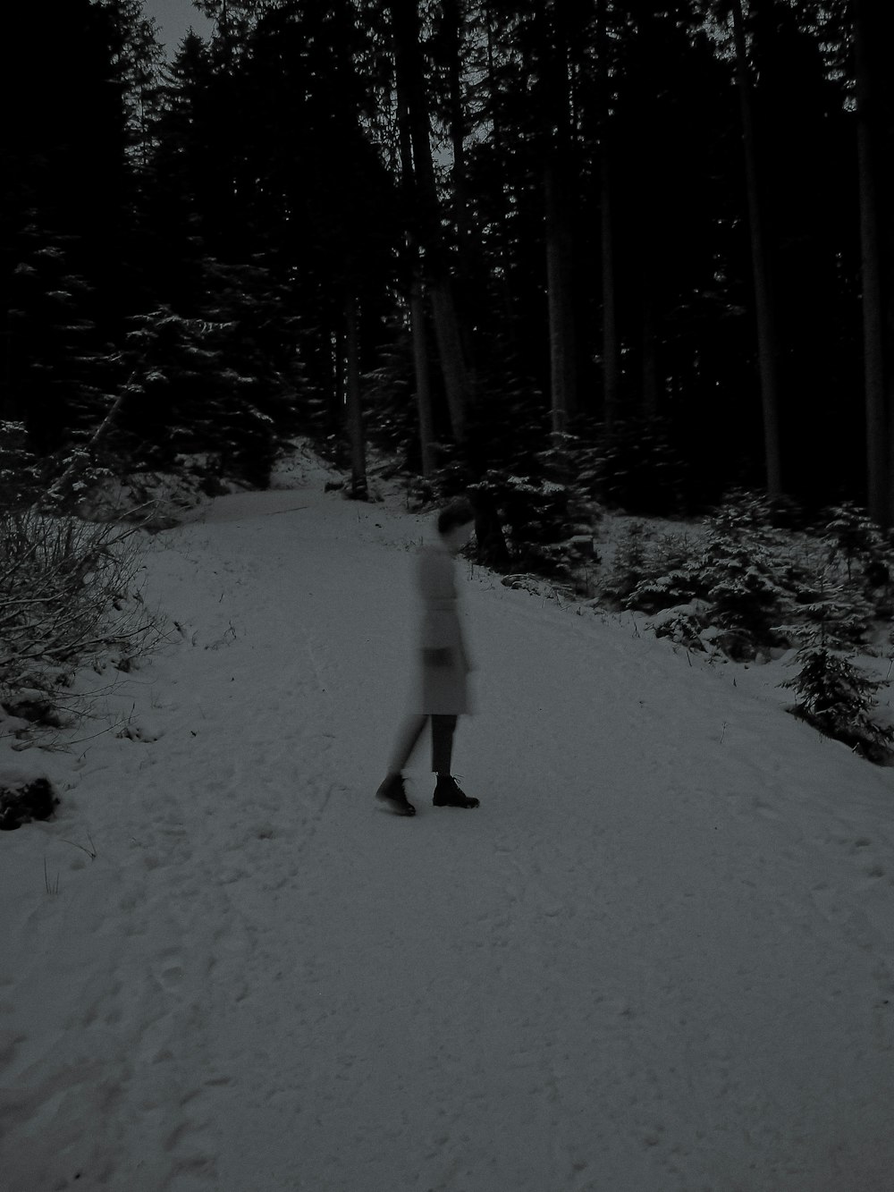 person in white jacket and black pants walking on snow covered ground during daytime