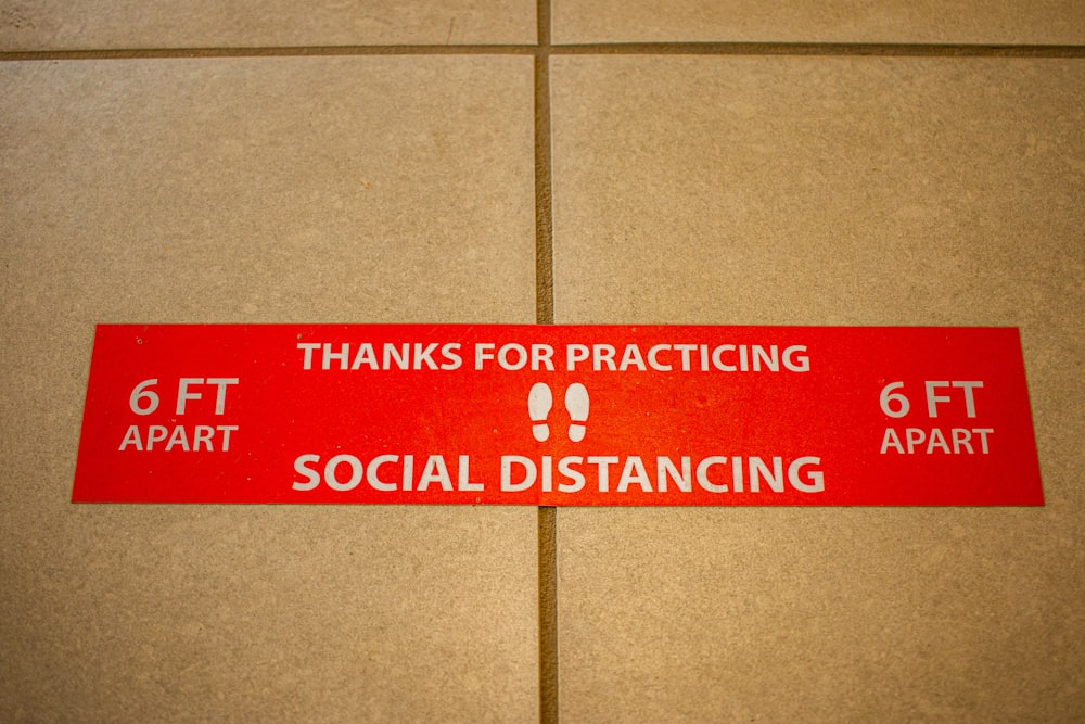 a red sign that says thanks for practicing social distancing