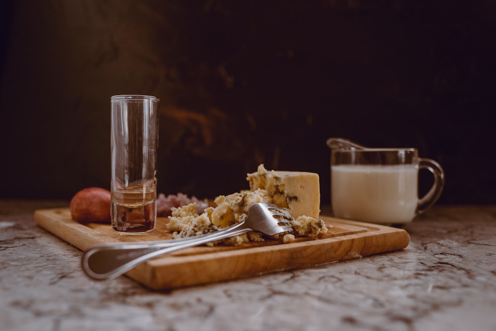 clear drinking glass on brown wooden chopping board